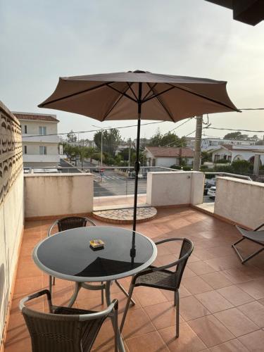 uma mesa e cadeiras com um guarda-sol numa varanda em Appartamento Geco Rosso em Noto Marina
