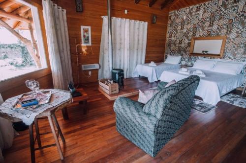 a bedroom with a bed and a table and chairs at Pousada Caminhos do Mel - Urubici - SC in Urubici