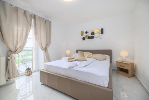 a white bedroom with a bed and a window at Apartman Toni in Krk