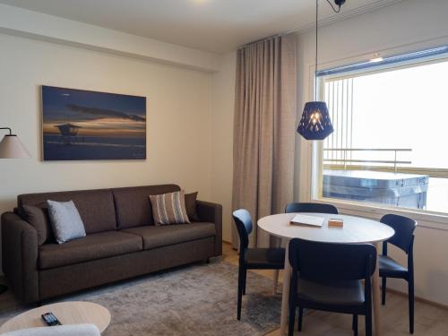a living room with a couch and a table at Nallikari Seaside Aalto Apartments in Oulu