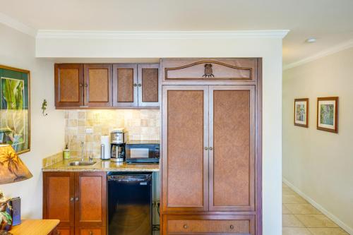 a kitchen with wooden cabinets and a black refrigerator at Islander on the Beach 309 - Studio in Kapaa