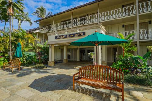 a bench and an umbrella in front of a hotel at Islander on the Beach 309 - Studio in Kapaa