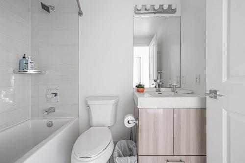a white bathroom with a toilet and a sink at Jarvis Residence in Toronto