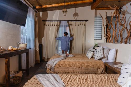 a man is looking out the window of a bedroom at Tierra Madre Hotel Boutique in Comonfort