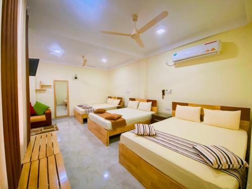 een hotelkamer met 2 bedden en een bank bij Sparkling Resort Kataragama in Kataragama
