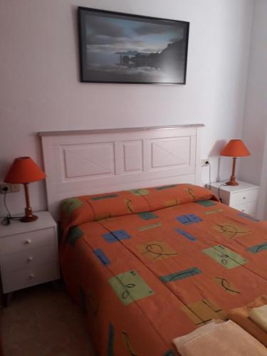 a bedroom with a bed with an orange comforter at Apartamento Playa Cárabos in Melilla