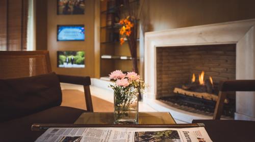 a vase of flowers on a table with a fireplace at Golden Age Athens Hotel in Athens