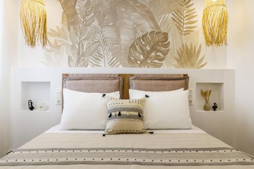 un letto con cuscini bianchi e una parete con piante di Potoki Apartments a Skopelos Town