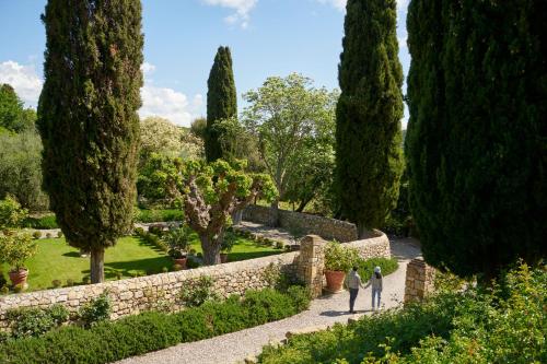 two people walking through a garden with trees at Castello Di Vicarello in Sasso dʼOmbrone