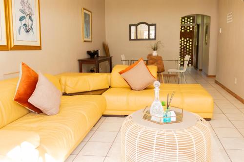 uma sala de estar com dois sofás amarelos e uma mesa em Lovely Spacious Two bedroom apartment em Joanesburgo