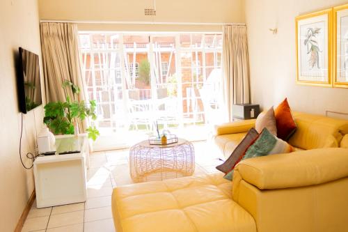 uma sala de estar com um sofá amarelo e uma mesa em Lovely Spacious Two bedroom apartment em Joanesburgo