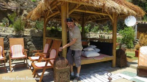 a man standing next to a bed in a gazebo at CASA LUXURY MADERA EN LAS MONTAÑAS DE TORROx in Málaga