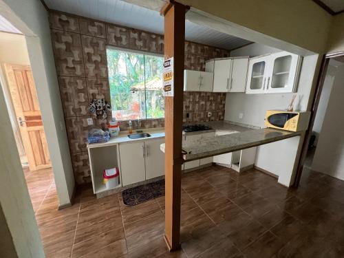 a small kitchen with white cabinets and a window at Hostel Rio do Boi in Praia Grande