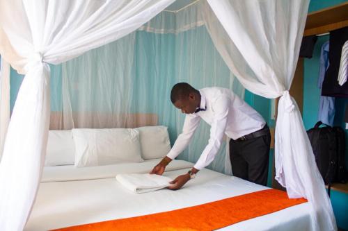 Ein Mann, der ein Bett in einem Zimmer macht. in der Unterkunft TROTTERS B&B KENOL in Gitura