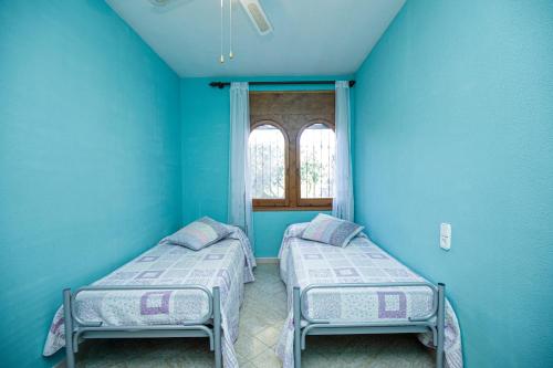Stay Barcelona Villa Miami في ميامي بلاتجا: سريرين في غرفة بجدران زرقاء