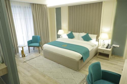 um quarto de hotel com uma cama e duas cadeiras em Soho Midtown em Ash Shumaysānī