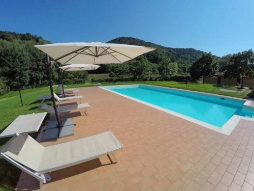 einen Pool mit einem Sonnenschirm und Stühlen sowie einem Pool in der Unterkunft Ferienhaus für 27 Personen in Monsagrati, Toskana Provinz Lucca in Monsagrati