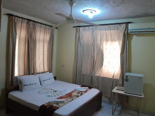 a bedroom with a bed and a window with curtains at Hotel Ideal in Dar es Salaam