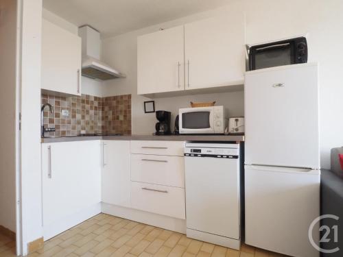 une cuisine avec des armoires blanches et un réfrigérateur blanc dans l'établissement Chez Fleur, au Grau-du-Roi