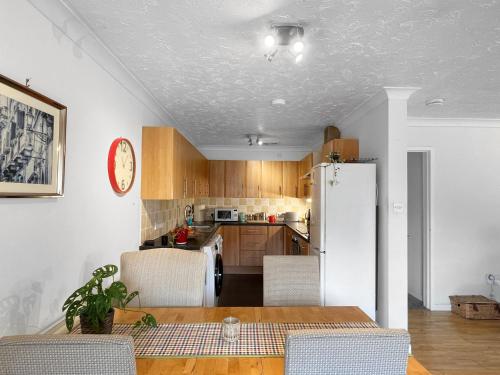 a kitchen with a table and a white refrigerator at Casa di Qeis a double bedroom ground floor flat with free parking in Chesterton