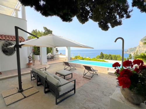 un patio con mesa, sillas y sombrilla en Villa Hibiscus en Capri