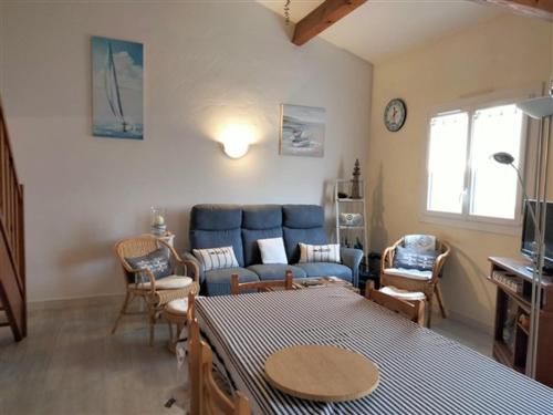 un salon avec un canapé bleu et des chaises dans l'établissement Maison T3 avec mezzanine, jardin paysagé et parking privatif, à 1 km de la plage de Tanchet - FR-1-331-228, à Les Sables-dʼOlonne