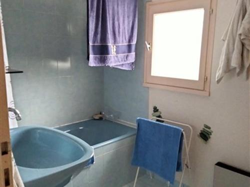 La salle de bains est pourvue d'une baignoire bleue et d'une fenêtre. dans l'établissement Maison T3 avec mezzanine, jardin paysagé et parking privatif, à 1 km de la plage de Tanchet - FR-1-331-228, à Les Sables-dʼOlonne