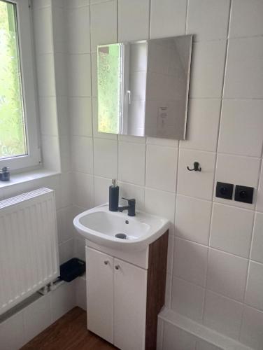 a white bathroom with a sink and a mirror at Domek całoroczny in Brenna