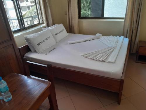 a bed with white sheets and pillows on it at Hotel Ideal in Dar es Salaam