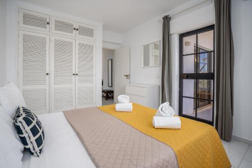 - une chambre avec un grand lit et des serviettes dans l'établissement Vila Rosa Flat, à Portimão