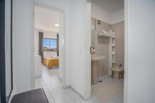a white bathroom with a sink and a toilet at Vila Rosa Flat in Portimão