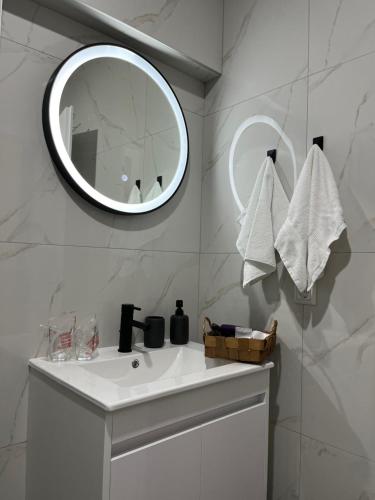 a white bathroom with a sink and a mirror at Apartments Indigo in Jajce