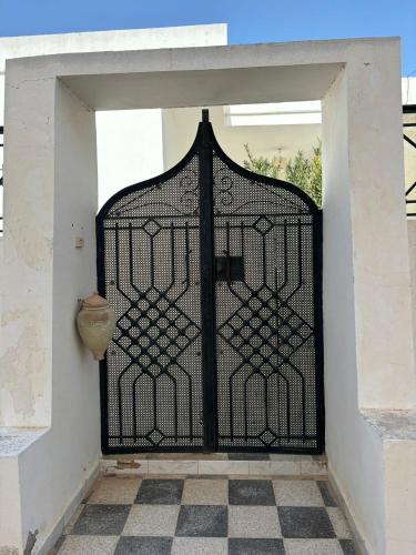 ein schwarzes Tor mit einer Vase im Türrahmen in der Unterkunft Jolie petite maison à Djerba Houmt Souk in Al Ḩārah al Kabīrah