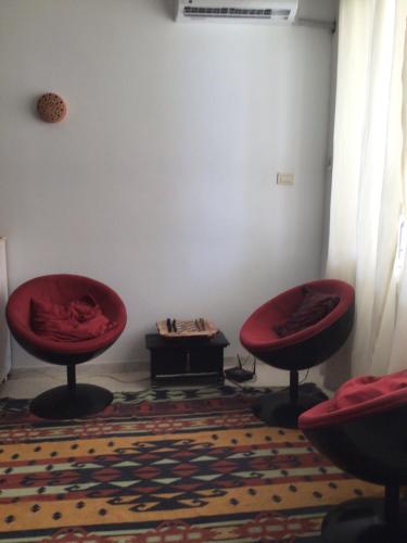 ein Zimmer mit zwei roten Stühlen und einem Tisch in der Unterkunft Jolie petite maison à Djerba Houmt Souk in Al Ḩārah al Kabīrah