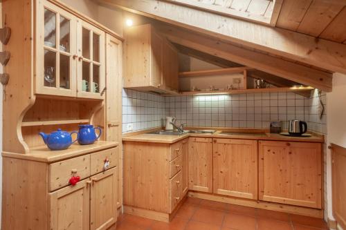 a kitchen with wooden cabinets and a sink at DolomiApartments - Appartamento Fiordaliso in Predazzo