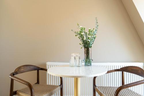 a table with two chairs and a vase with flowers at Numa Copenhagen Nørrebro in Copenhagen