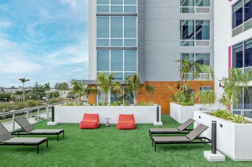 an apartment patio with red chairs and grass at Aloft Fort Lauderdale Airport & Cruise Port in Fort Lauderdale