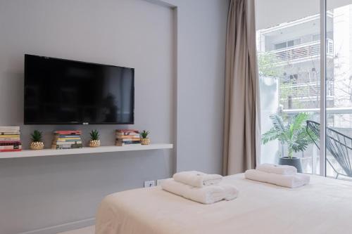 Habitación blanca con 2 toallas en una cama y TV en Segui 3900 'a' - Loft Palermo Chico en Buenos Aires