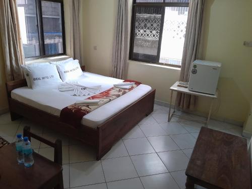 a bedroom with a bed in a room with windows at Hotel Ideal in Dar es Salaam