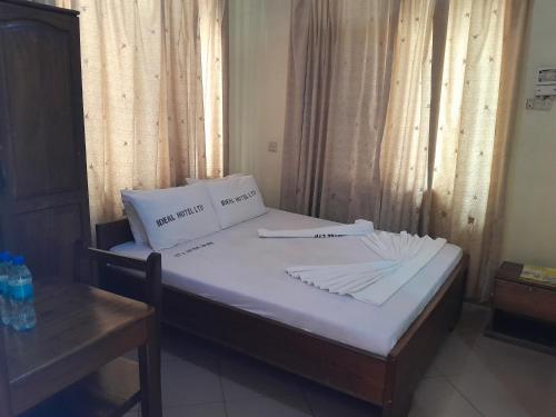 a bed with white sheets and pillows in a room at Hotel Ideal in Dar es Salaam