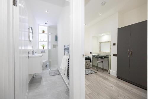 a bathroom with white walls and a sink and a mirror at WestPoint Luxury Apartment in Manchester