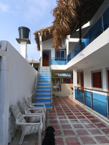 a black dog sitting in front of a building with stairs at HABITACIONES EN casa de playa in Coveñas