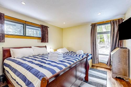 a bedroom with a bed with a blue and white comforter at Lakeside Lullaby in Wolfeboro