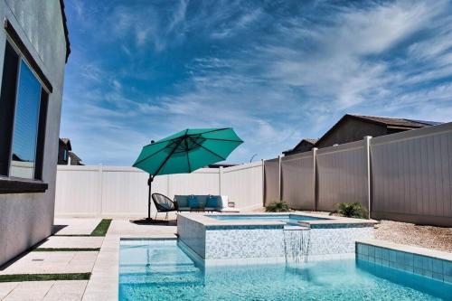 a pool with a green umbrella next to a fence at Modern Desert Oasis in Coachella