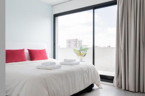 Un dormitorio con una cama blanca con almohadas rojas y una ventana en Fliphaus Zapiola 2300 'e' - 1 Bd Belgrano en Buenos Aires