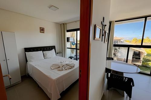 a bedroom with a bed and a table and a window at Flat Kandela - Maracaípe in Porto De Galinhas