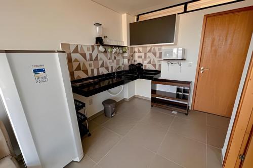 a kitchen with a white refrigerator in a room at Flat Kandela - Maracaípe in Porto De Galinhas
