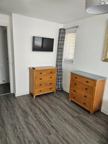 a room with a dresser and a tv on a wall at 5 Fulmar Road**Next to West Beach and Golf Course in Lossiemouth