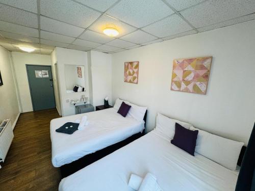 two beds in a room with white walls at Burlington West hotel in Blackpool