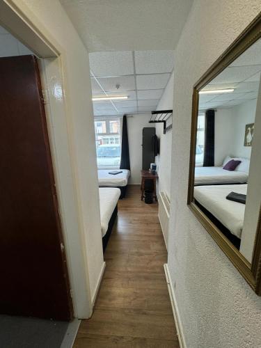 a hallway of a room with two beds and a mirror at Burlington West hotel in Blackpool